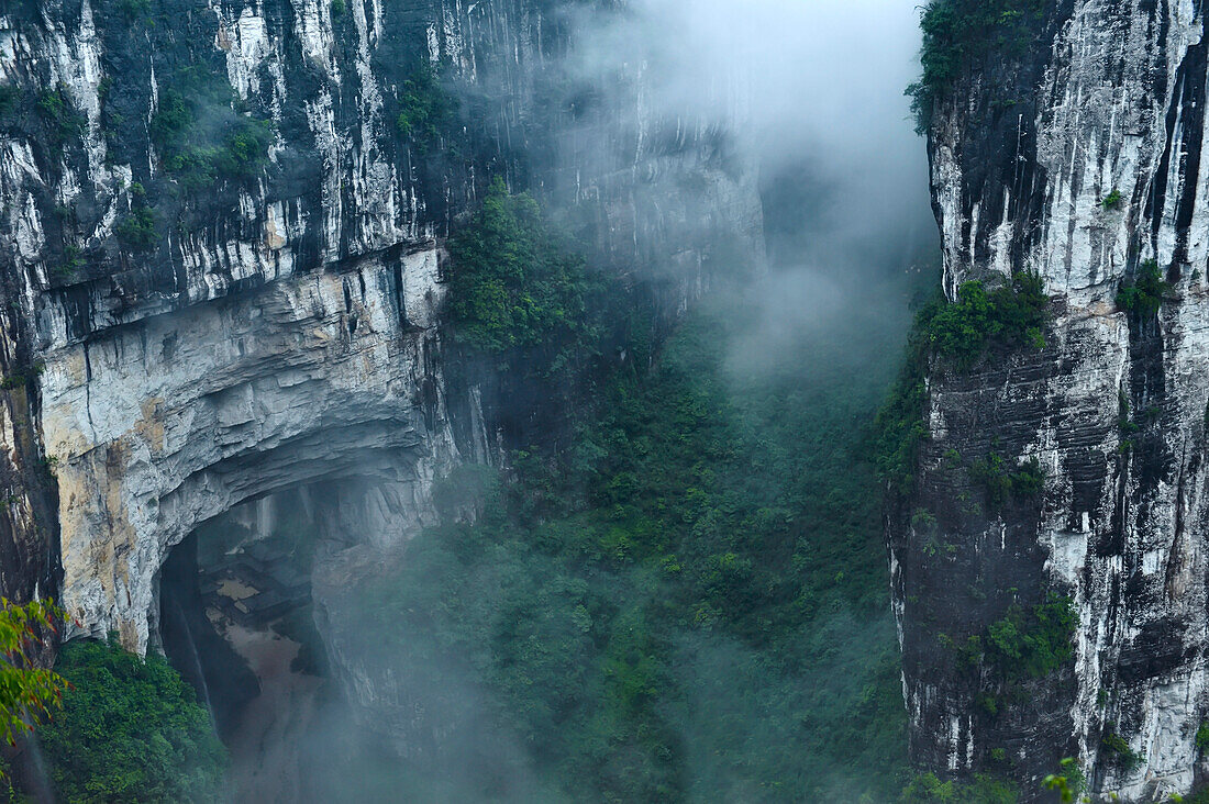 Nachdem der Regen vorbei ist und die Wolken vom Grund der Schluchten in Sanqiao, oder den Drei Natürlichen Brücken, aufsteigen, kommen große Kalksteinfelsen zum Vorschein; Wulong, Provinz Chongqing, China.