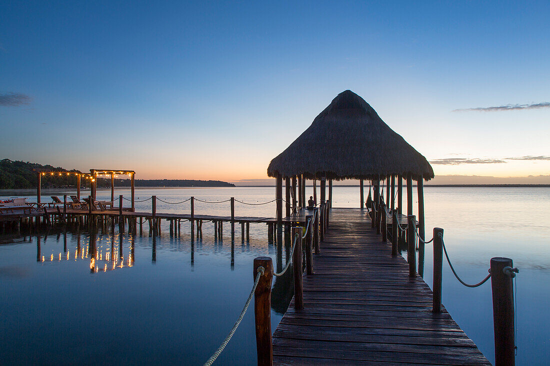 Silhouette des Tiki-Hütten-Pavillons auf dem Dock des Rancho Encantado Eco-Resort & Spa in Bacalar bei Sonnenaufgang; Quintana Roo, Mexiko