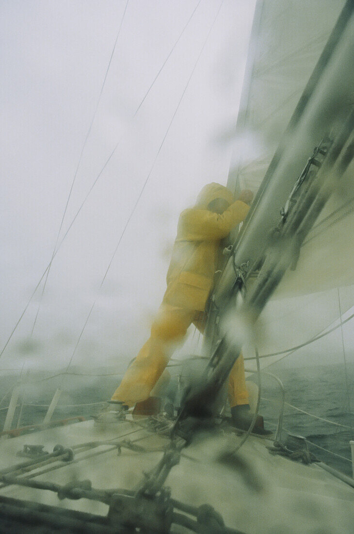 Man reefing mainsail in heavy weather.; Lake Champlain, Vermont.