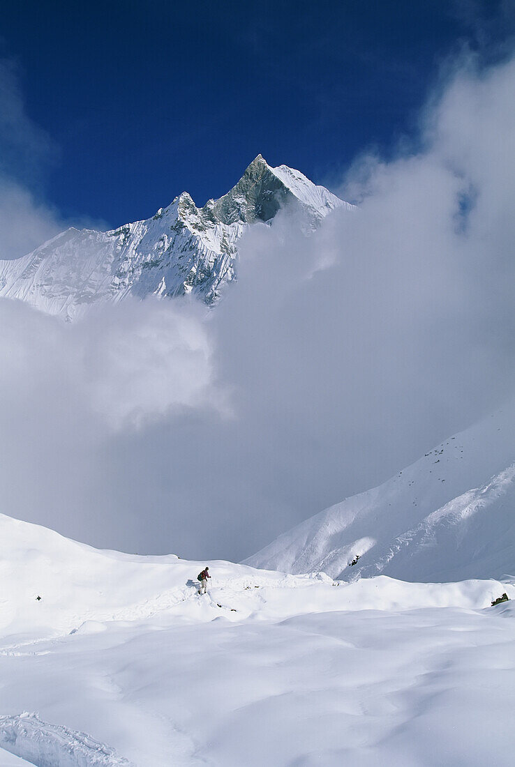 Man hiking down from Annapurna base camp into the clouds, Nepal.; ANNAPURNA, NEPAL.