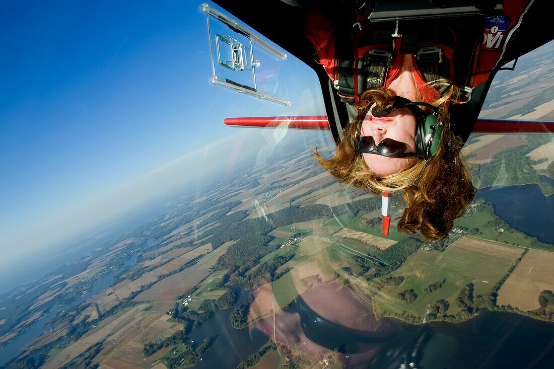 A female aerobatic pilot flies upside down.; Eastern Shore of Maryland.