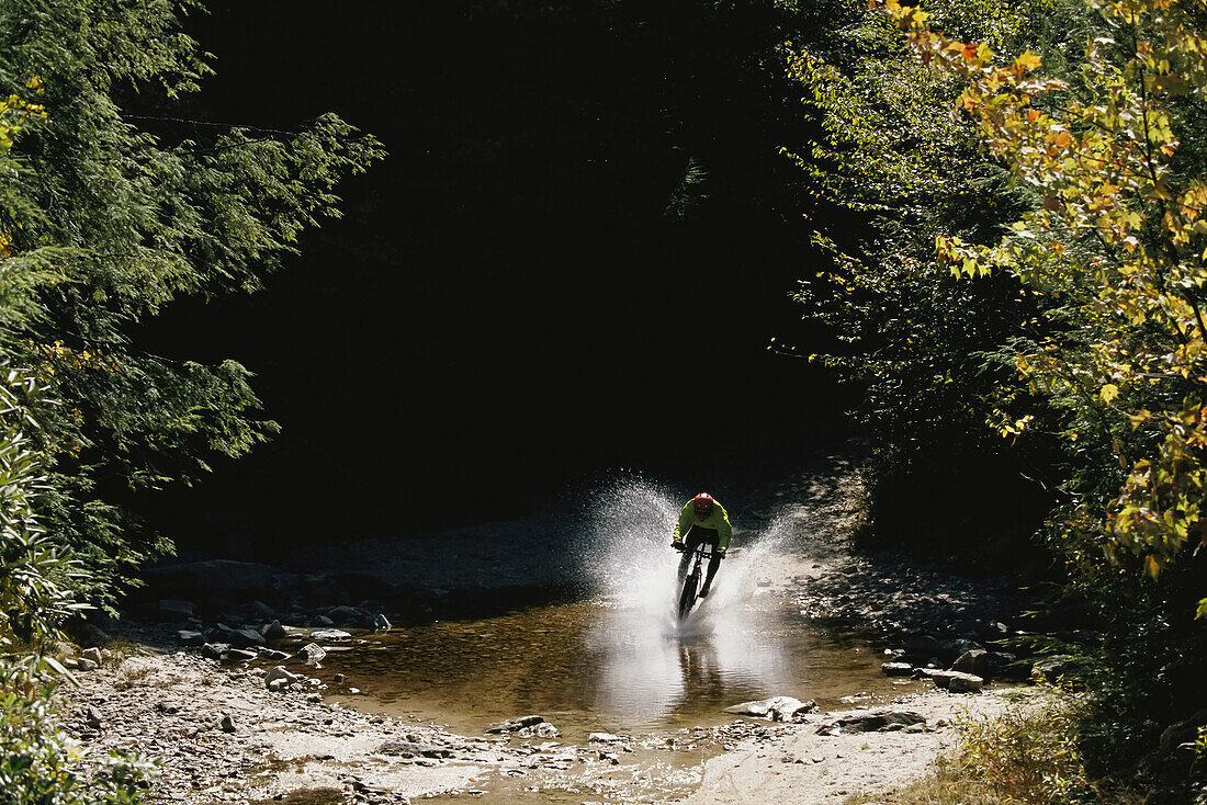 Mountain biker splashing through water at high speed, Canaan Valley.; CANAAN VALLEY, WEST VIRGINIA.