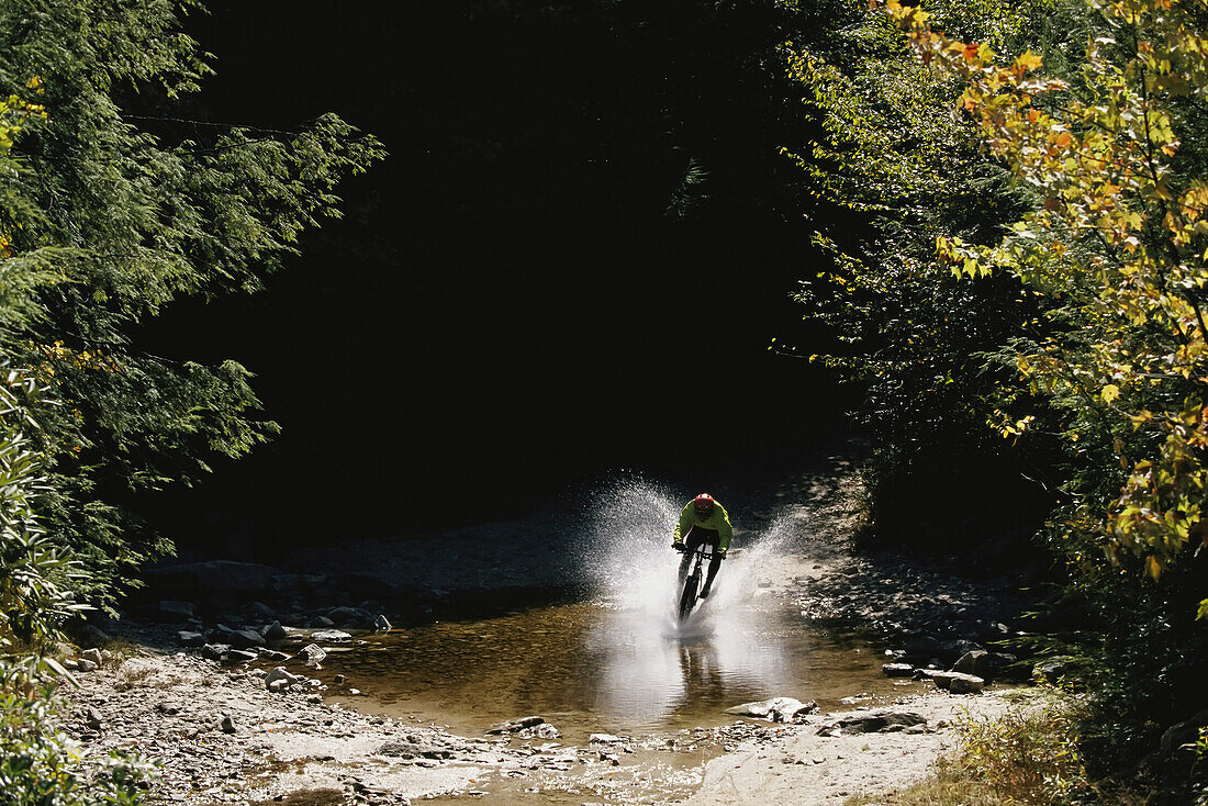 Mountainbiker spritzt mit hoher Geschwindigkeit durchs Wasser, Canaan Valley; CANAAN VALLEY, WEST VIRGINIA.