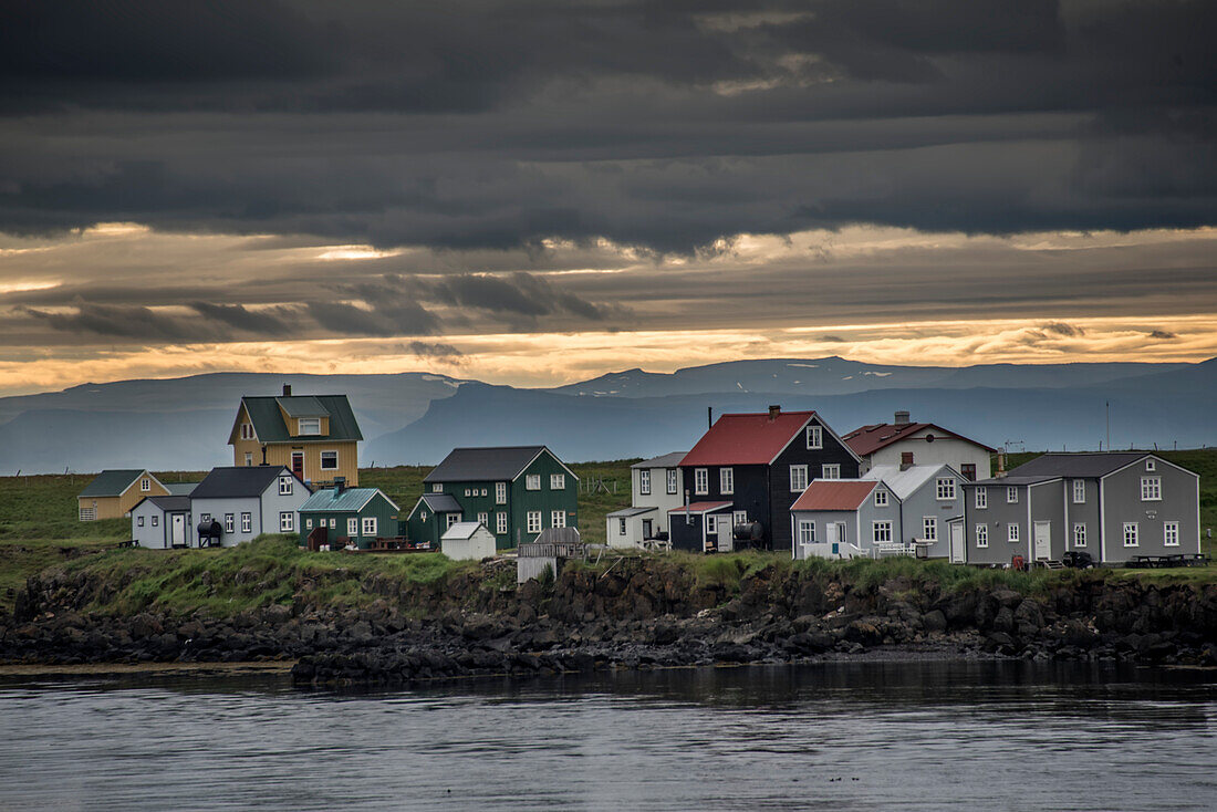 Colorful wooden houses along the shoreline on Flatey Island, part of a cluster of about forty large and small islands and islets located in Breiðafjörður on the northwestern part of Iceland; Western Islands, Iceland