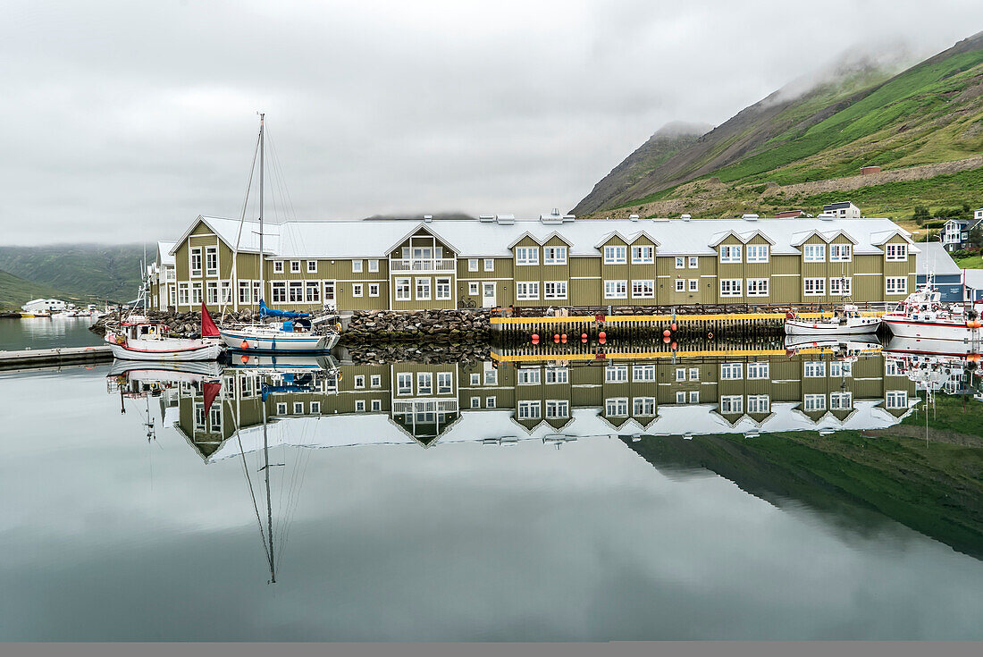 Siglo Hotel along the dock in the harbor of Siglufjörður, a small fishing town of approximately 1300 people, on a narrow fjord of the same name on the northern coast of Iceland. It grew up around the herring industry which has since declined. It is the site of the award winning The Herring Era Museum, Iceland's largest maritime museum; Siglufjordur, Northeastern Region, Iceland