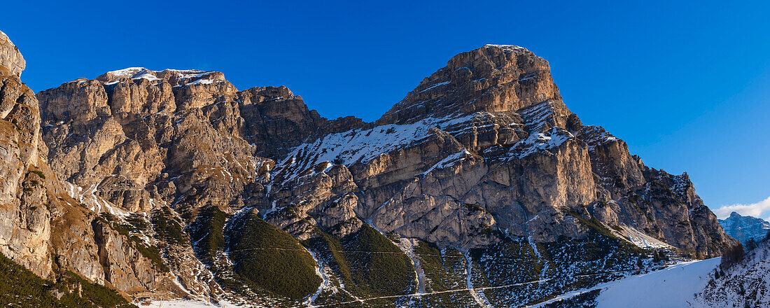 Rocky peaks of Sassongher Mountain covered in snow against a bright blue sky at Colfosco Corvara in Alta Badia Mountain Region; Dolomites, Italy