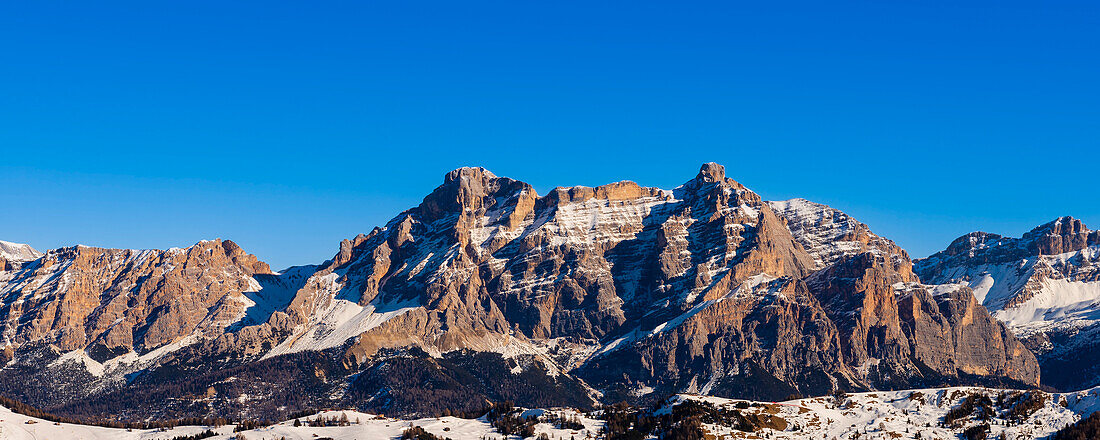 View towards Tofana and Lagazuoi Mountains with snow covered rock faces against a bright blue sky in Alta Badia Mountain Region; Trentino-Alto Adige, Dolomites, Italy