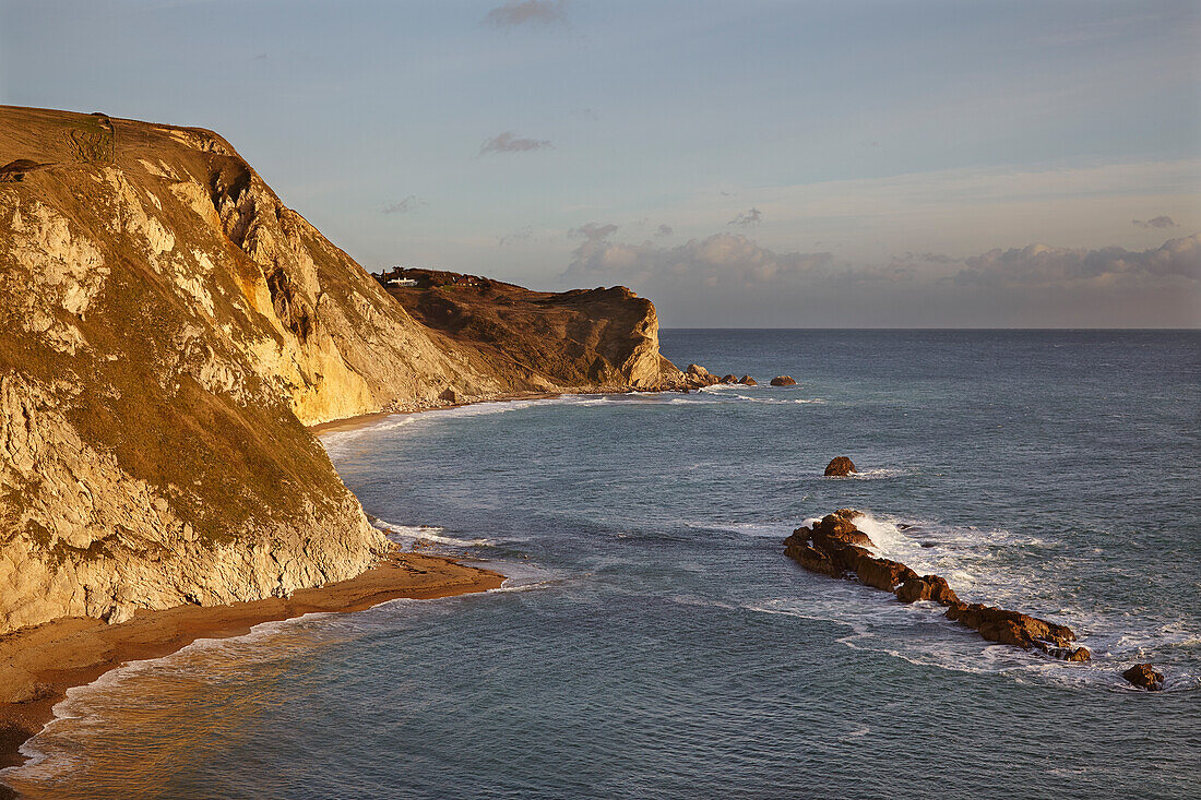 Sonnenbeschienene Kreidefelsen bei Lulworth Cove mit Blick auf den Atlantik an der Jurassic Coast; Dorset, England, Großbritannien
