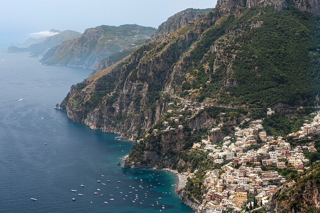 Luftaufnahme der Klippenstadt Positano mit an der Amalfiküste vertäuten Booten und Blick auf Capri; Positano, Salerno, Italien