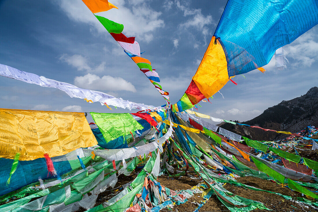 Bunte Gebetsfahnen auf einer Bergkuppe vor blauem Himmel; Amdo, Tibet