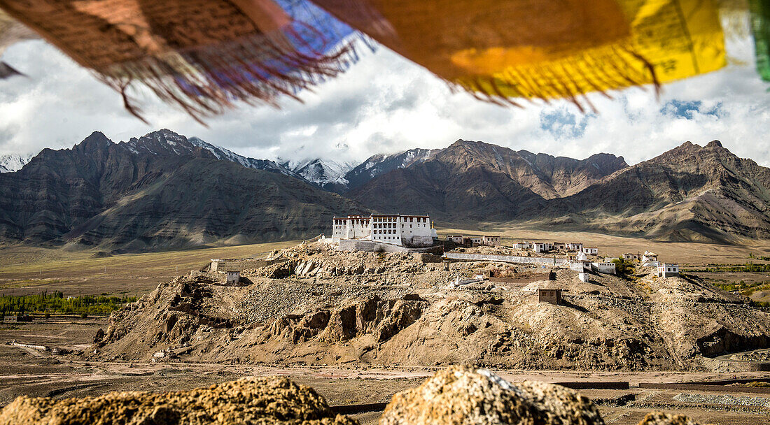 Overview of the Tibetan Buddhist Stakna Gompa on a rocky outcrop in the foothills of the Himalayas, the Leh District, with colorful prayer flags flying above; Jammu and Kashmir, India