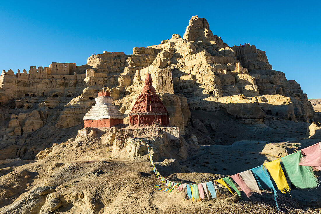 Ruins of the Guge Kingdom with prayer flags in the mountainous landscape of the Sutlej Valley in the Himalayan Mountains; Tsaparang, Zanda, Tibetan Autonomous Region, Tibet