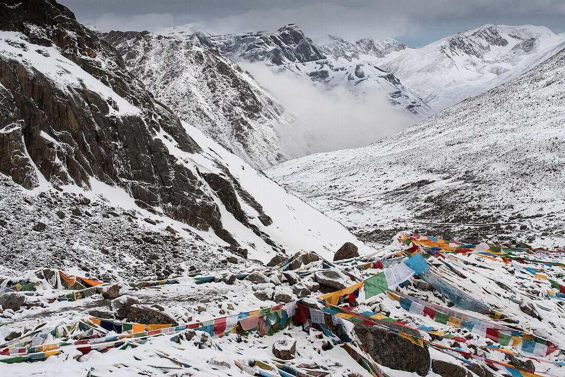 Drolma-La Pass and the snow covered mountain landscape at Mount Kailash with prayer flags; Burang County, Ngari Prefecture, Tibet Autonomous Region, Tibet