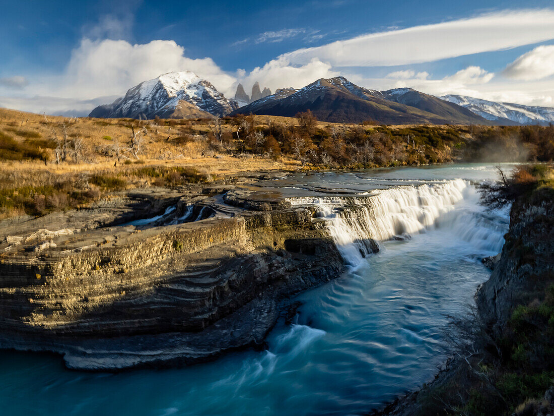 Blick auf die Cascada Rio Paine mit den Cuernos Del Paine Berggipfeln in der Ferne; Torres del Paine National Park, Patagonien, Chile