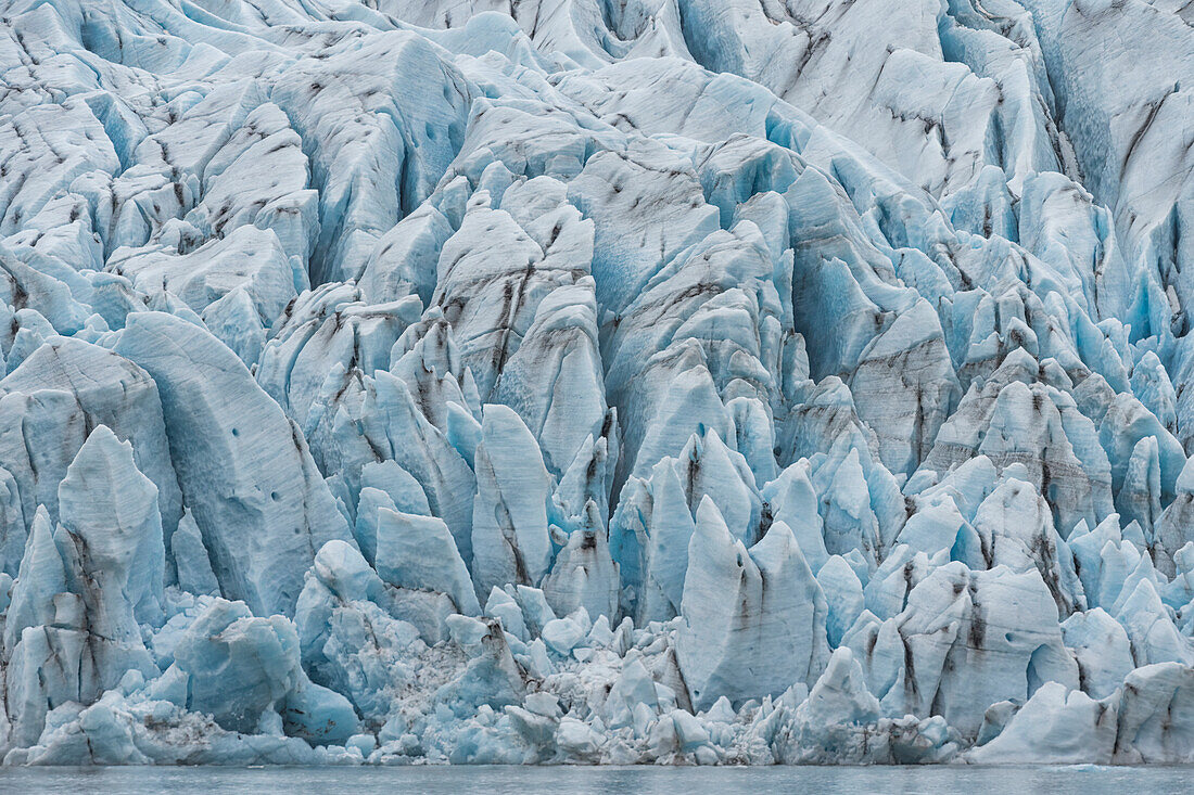 Atemberaubender Blick auf die von Schlick durchzogenen, zerklüfteten blauen Eisformen eines Gletscherterminus; Südisland, Island