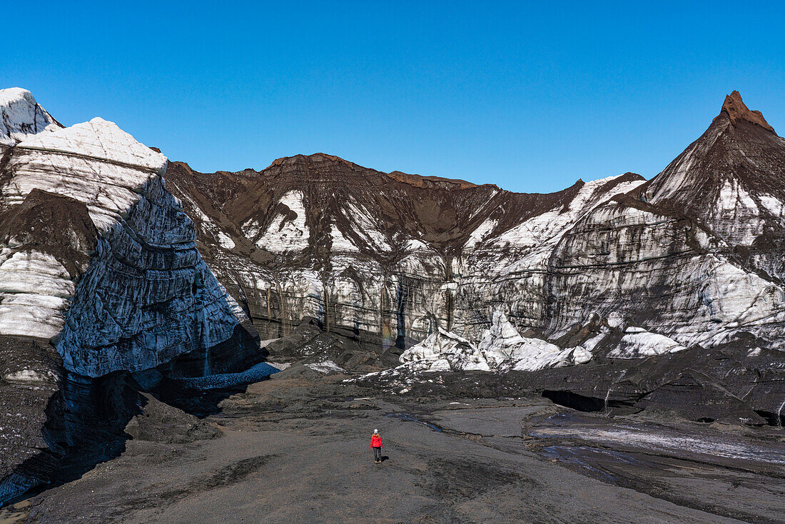 Frau spaziert durch die Landschaft in der Nähe eines Gletschers im Süden Islands; Vik, Südisland, Island