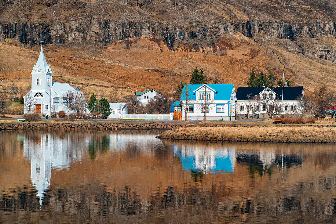 Gebäude von Seydisfjordur spiegeln sich in einer kleinen Lagune, Kirche und Häuser in der östlichen Region von Island; Island