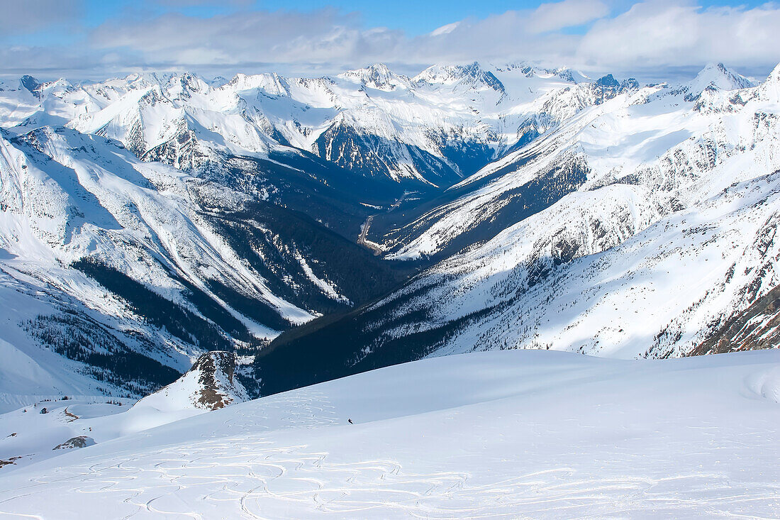 Ein Backcountry-Snowboarder fährt ein Schneefeld in der Nähe des Rogers Passes in den Selkirk Mountains des Glacier National Park hinunter; British Columbia, Kanada