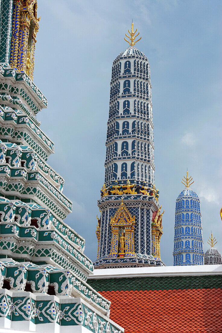 A line of ornate, colorful Thai spires, or prangs.; The Grand Palace, Bangkok, Thailand.