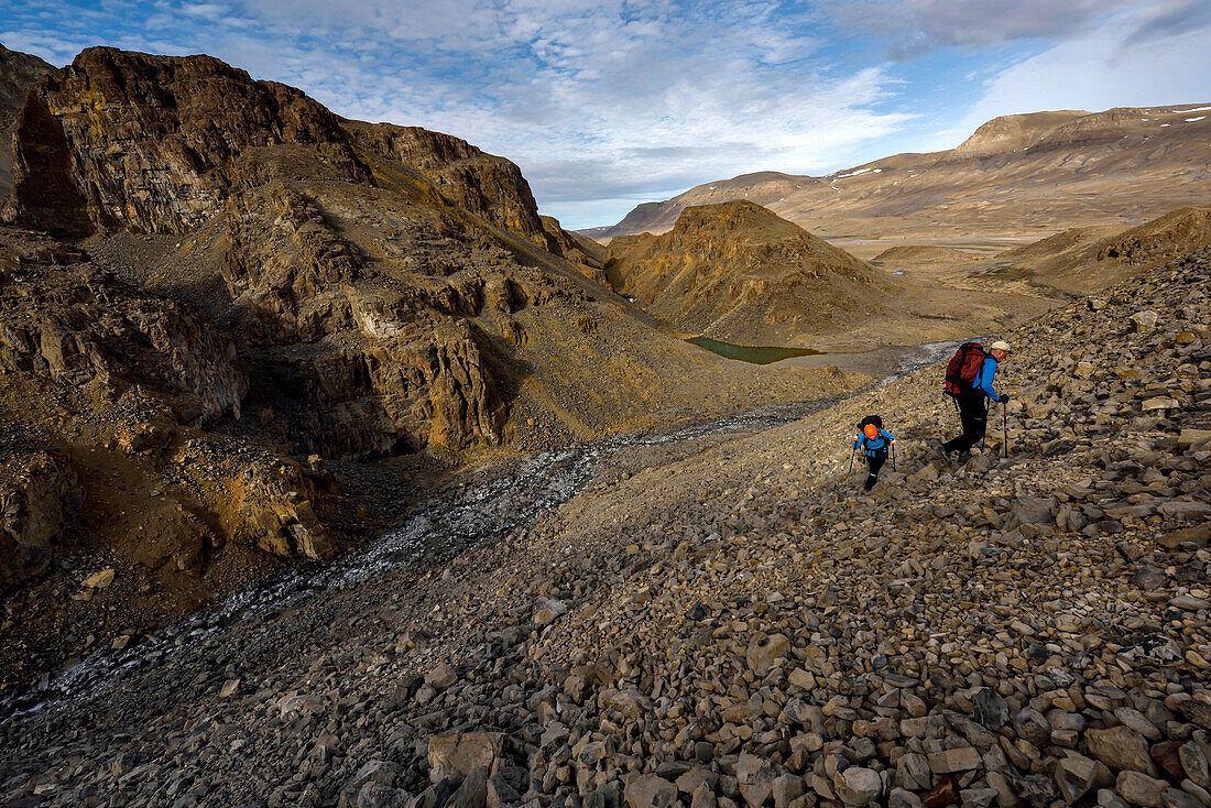 After finishing recording and documenting the first cave the team encounted, expedition team members climb one of the many scree slopes of rocks up onto another level to find the more larger and significant caves that they had previously read about.