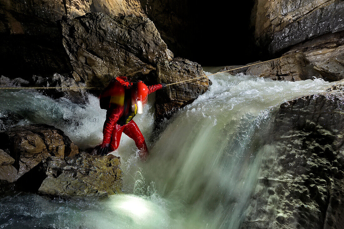 Ein Höhlenforscher wandert über das weiße Wasser in einer tiefen unterirdischen Höhle.