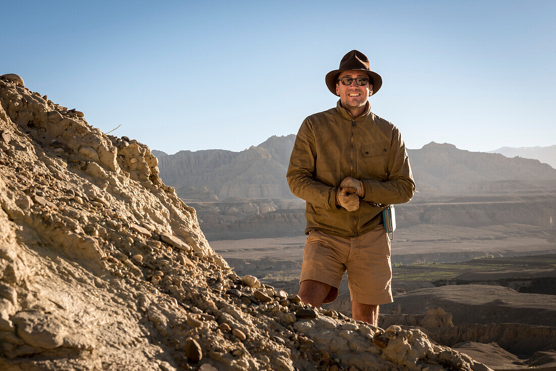 Portrait of Explorer on the mountainside at The Guge Kingdom Ruins and the stark landscape of the Sutlej Valley in the Himalayan Mountains; Tsaparang, Zanda, Tibetan Autonomous Region, Tibet