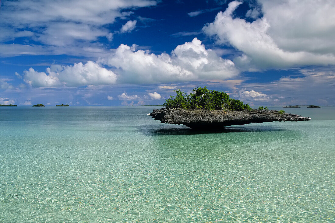 Pilzinsel, klares blaues Wasser und ein wolkenverhangener Himmel.