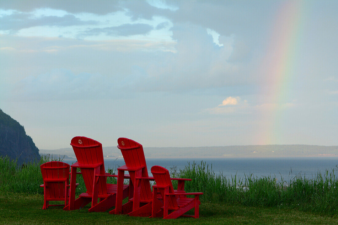 Adirondack-Stühle mit Blick auf die Bay of Fundy und einen Regenbogen am Himmel; Alma, Fundy National Park, New Brunswick, Kanada.