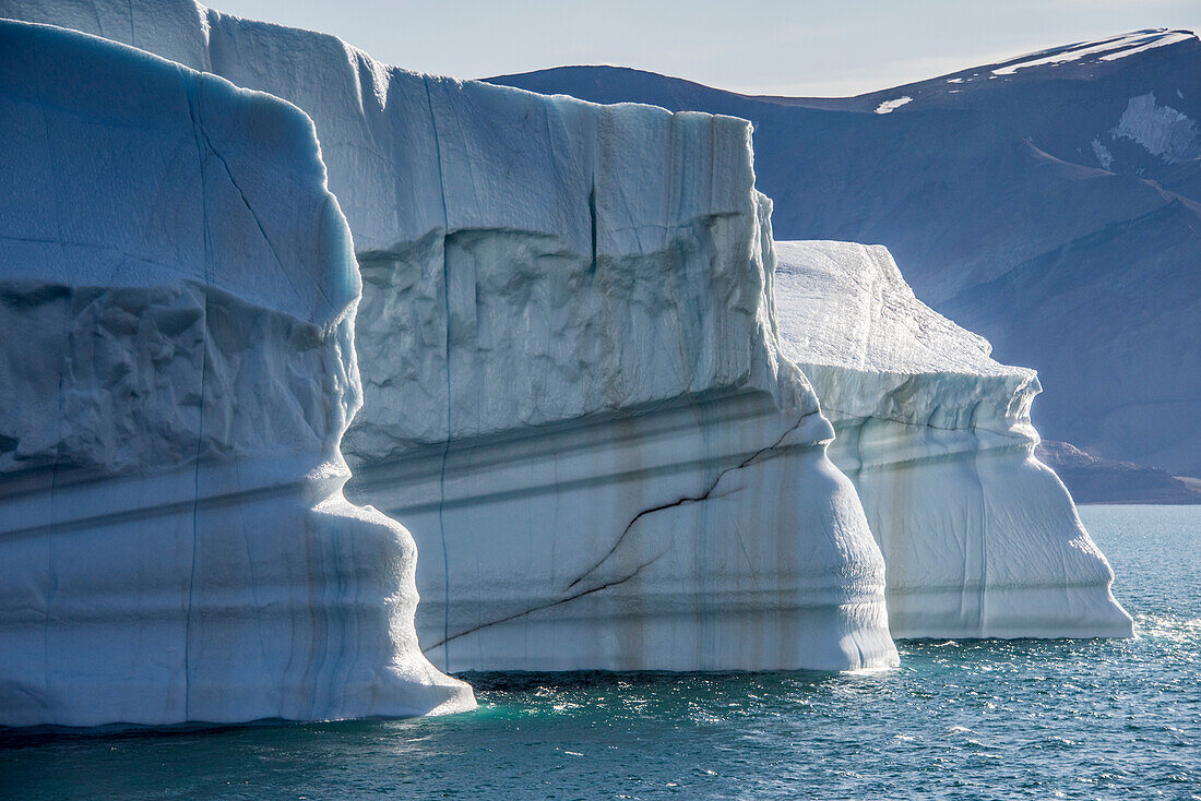 Nahaufnahme eines großen Eisbergs mit Schlickstreifen, der im eisblauen Wasser des Kaiser-Franz-Joseph-Fjords in Grönland treibt; Ostgrönland, Grönland