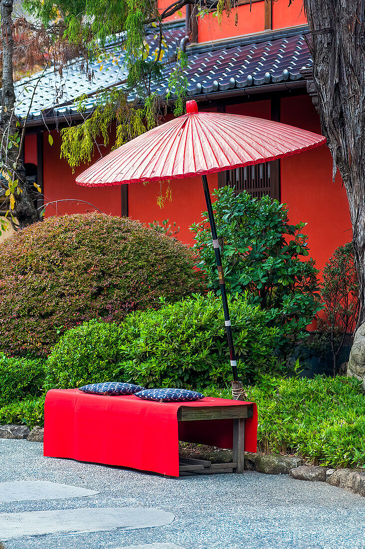 Red umbrella over a bench outside a temple; Tokyo, Japan