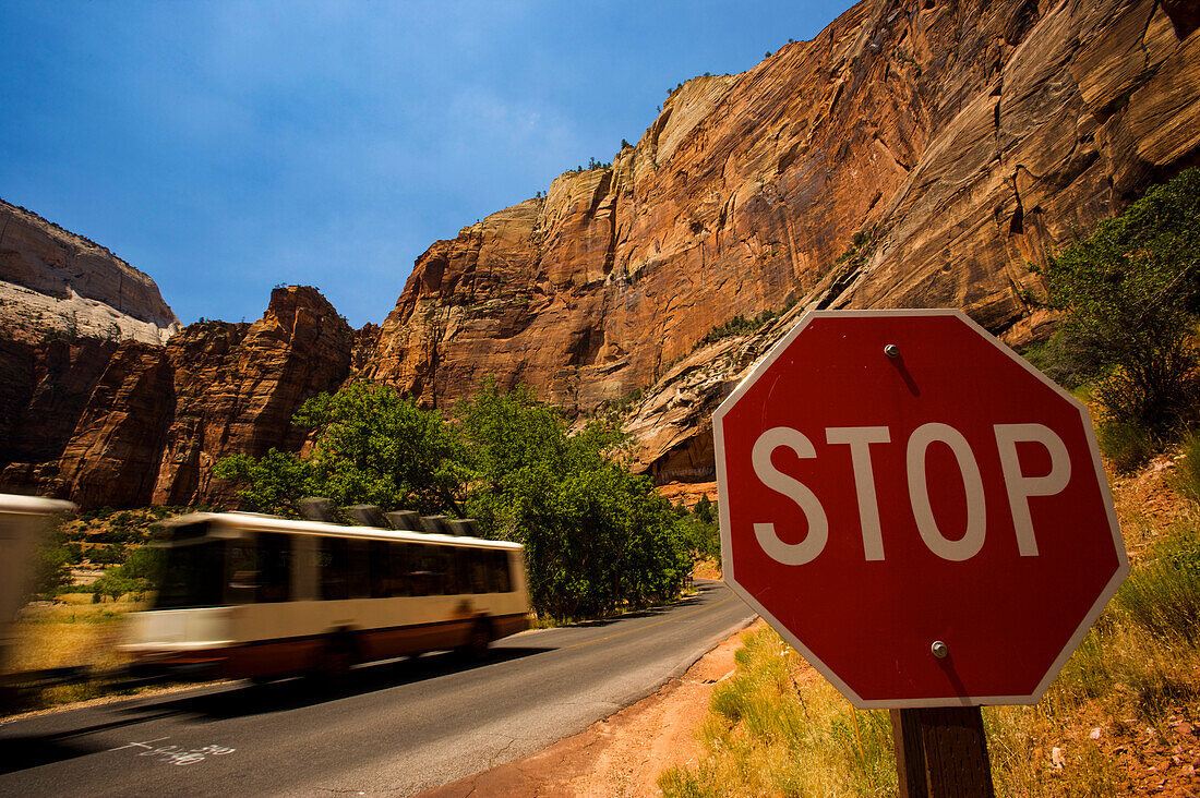 Propanbetriebener Shuttlebus passiert ein Stoppschild im Zion National Park; Utah, Vereinigte Staaten von Amerika