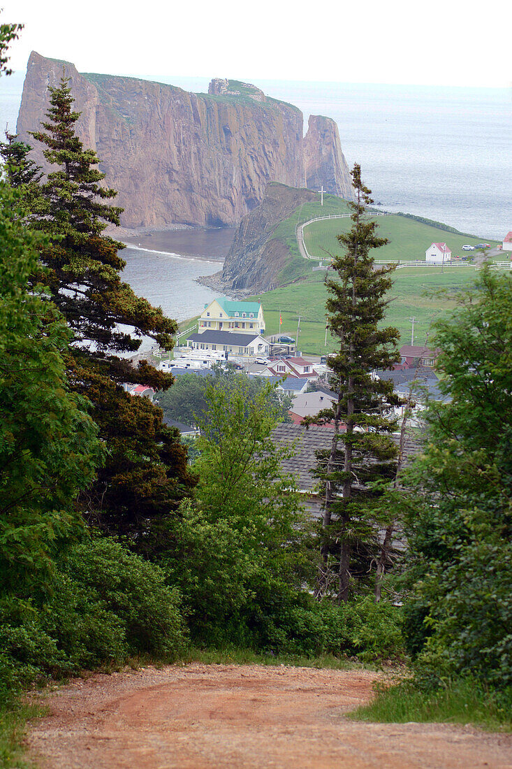 View of the town of Perce, and Perce Rock from a nearby hill.; Perce, Gaspe Peninsula, Quebec, Canada.