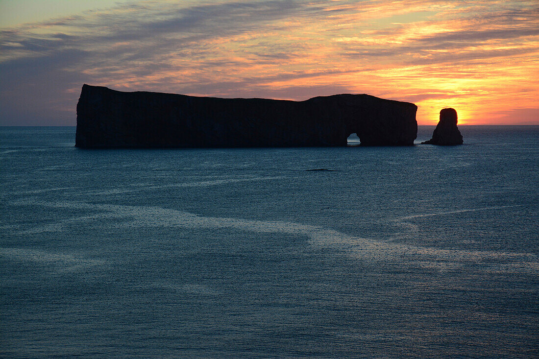 Silhouetted Perce Rock at sunrise.;   Ile Bonaventure et du Rocher-Perce National Park, Gaspe Peninsula, Quebec, Canada.
