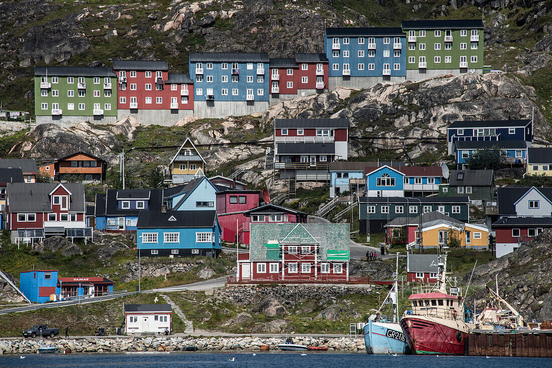 Close-up view of the colorful buildings on the rocky cliffs along the shore in the seaport town of Qaqortoq on Greenland's southern tip; Qaqortoq, Southern Greenland, Greenland