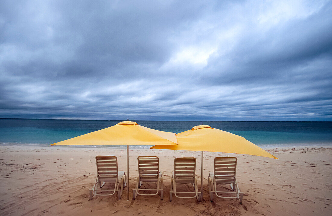 Lounge chairs and umbrellas on the beach on a cloudy day; Turks and Caicos Islands, West Indies
