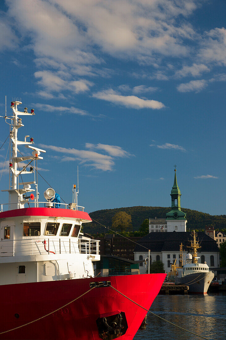 Angedockte Boote im Hafen von Bergen, mit einem Kirchengebäude am Ufer; Bergen, Norwegen