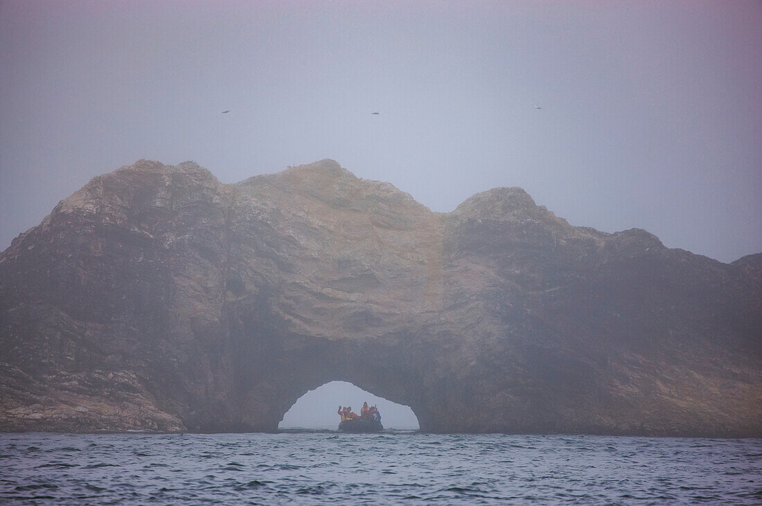 Ecotourists explore Bear Island in an inflatable raft; Bjornoya or Bear Island, Svalbard Archipelago, Norway