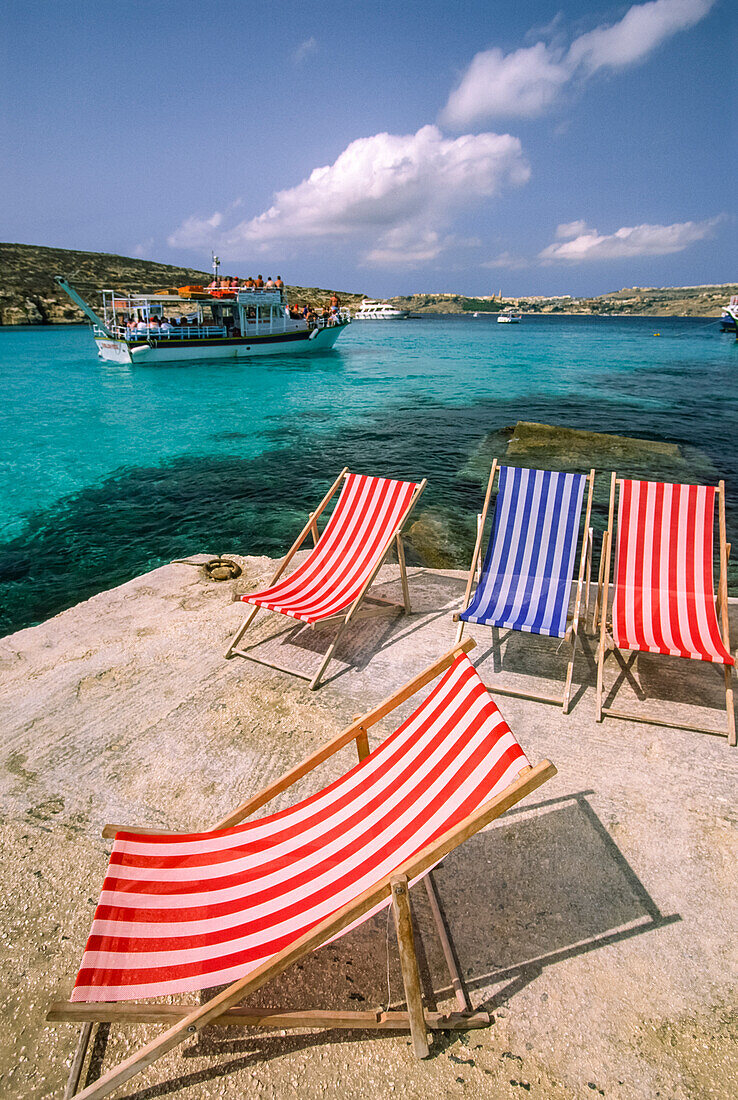 Kreuzfahrtschiff fährt an einer Mittelmeerküste mit Liegestühlen vorbei; Comino Island, Malta