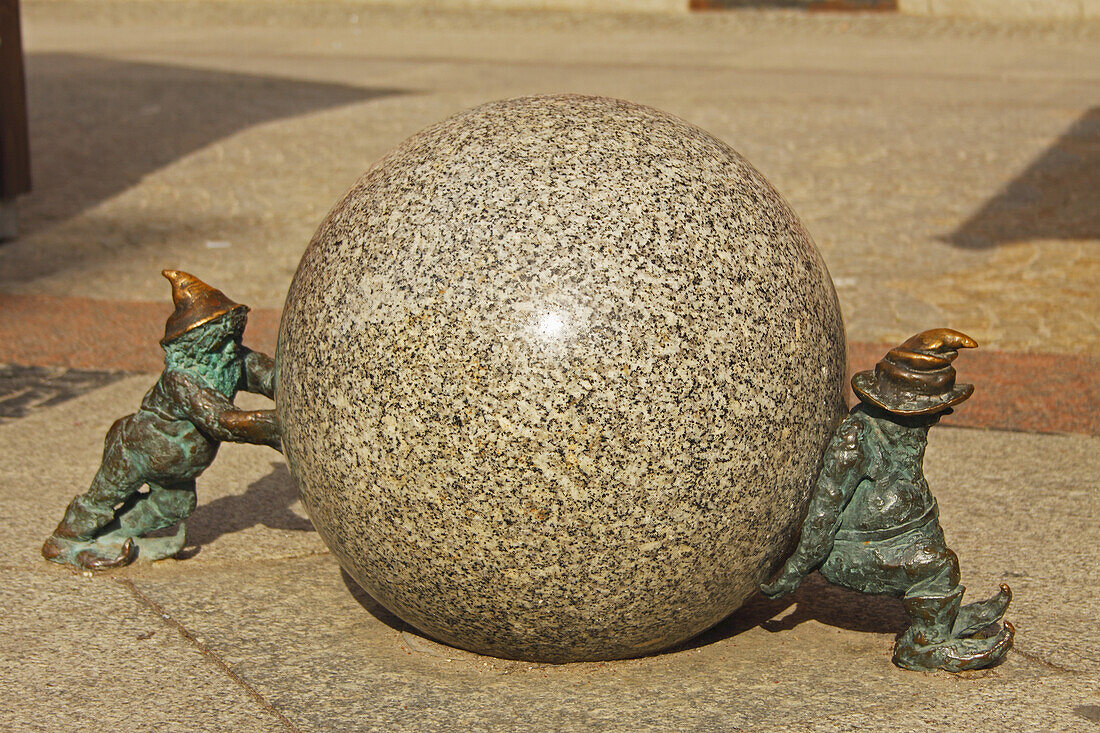 Bronze Sculptures Of Two Gnomes Pushing A Boulder; Wroclaw Poland