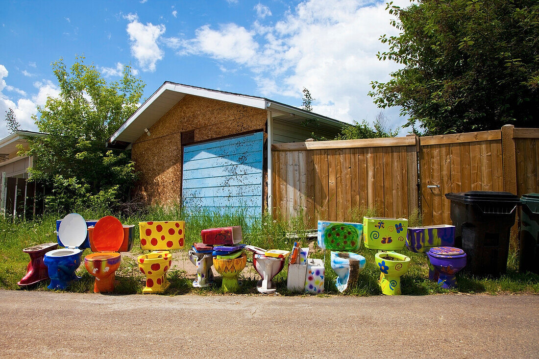 Colourful And Decorated Toilets Lined Up On The Side Of The Road Outside A House; Spruce Grove Alberta Canada