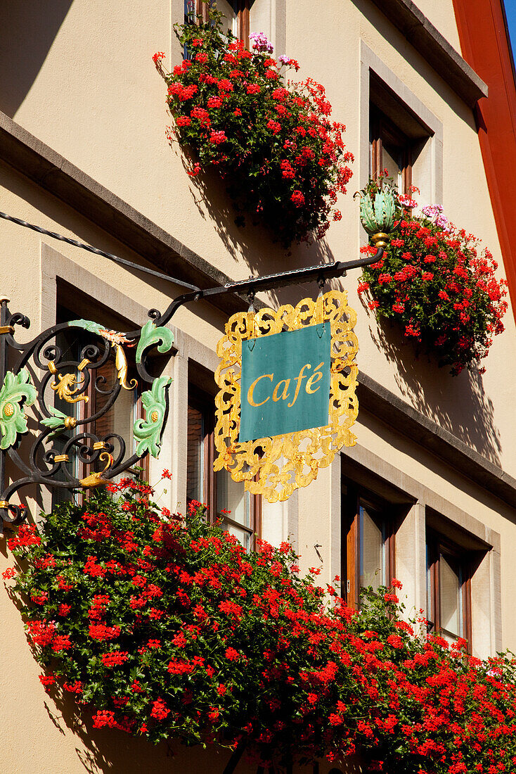 Coffee Shop Sign Hanging From The Side Of A Building With Red Flowers In Window Planter Boxes; Rothenburg Ob Der Tauber Bavaria Germany