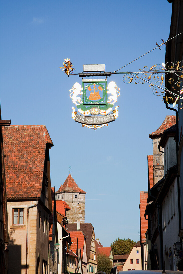 Ein Schild hängt von einem Gebäude gegen einen blauen Himmel; Rothenburg Ob Der Tauber Bayern Deutschland