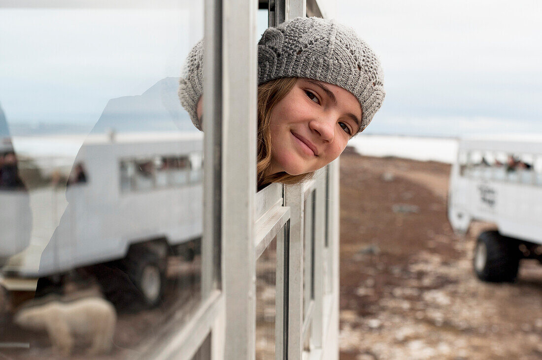 A Girl Looks Out The Window Of A Tundra Vehicle On A Polar Bear Expedition; Churchill Manitoba Canada