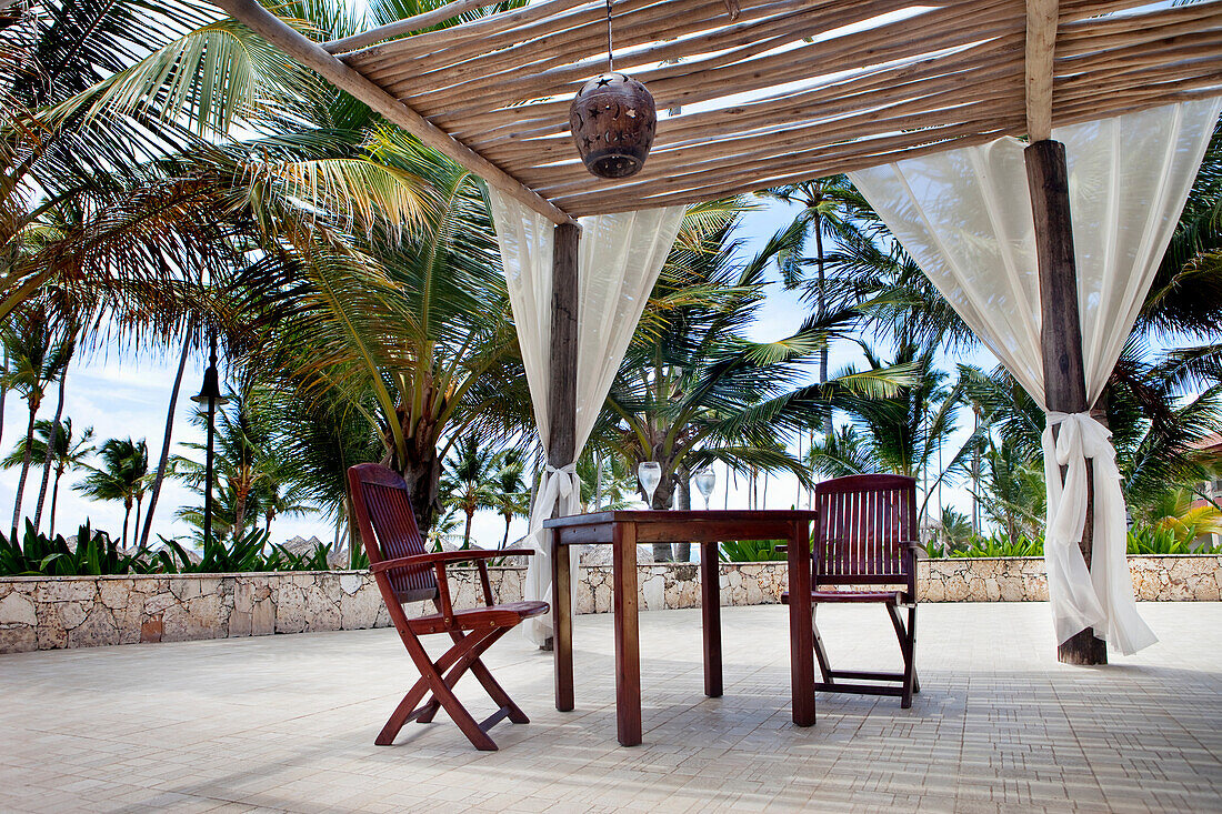 A Table And Chair Under A Canopy With Palm Trees Surrounding It; Punta Cana La Altagracia Dominican Republic