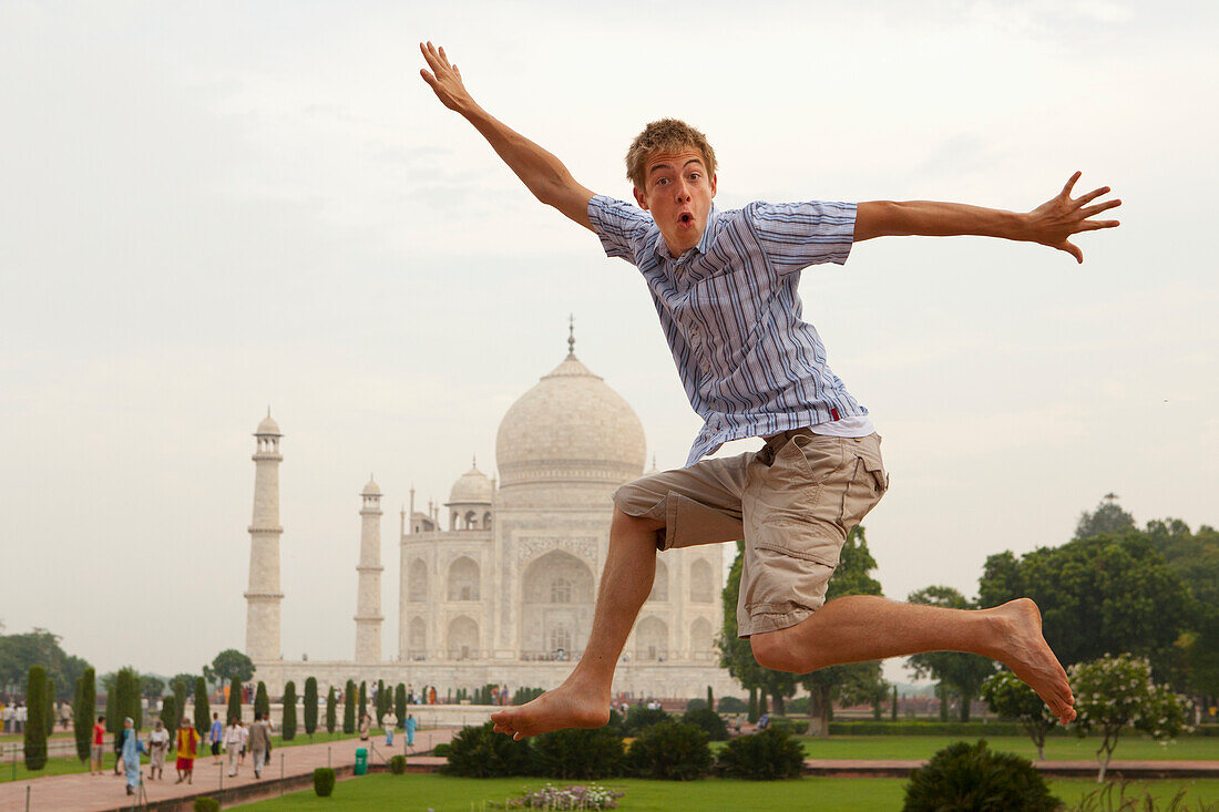 Ein junger Mann springt in die Luft mit dem Taj Mahal im Hintergrund; Agra Uttar Pradesh Indien