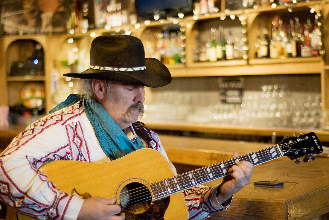 Cowboy beim Gitarrenspiel in einem Saloon; Bragg Creek Alberta Kanada