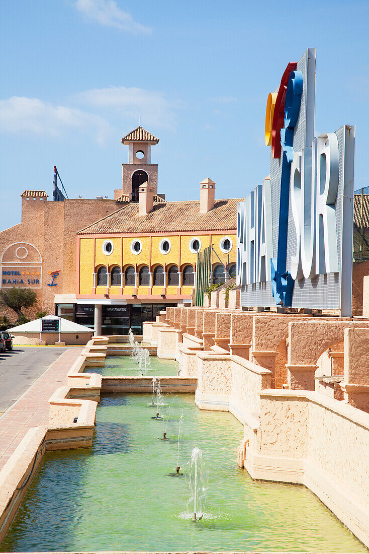 Wasserfontänen vor einem Schild mit dem Stadtnamen; Bahia Sur, San Fernando, Andalusien, Spanien