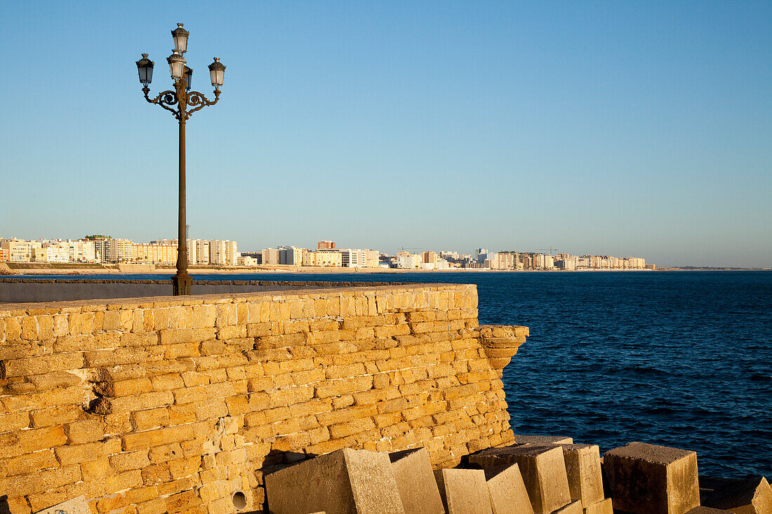 Ein Laternenpfahl und Holzkisten am Ufer; Cádiz, Andalusien, Spanien