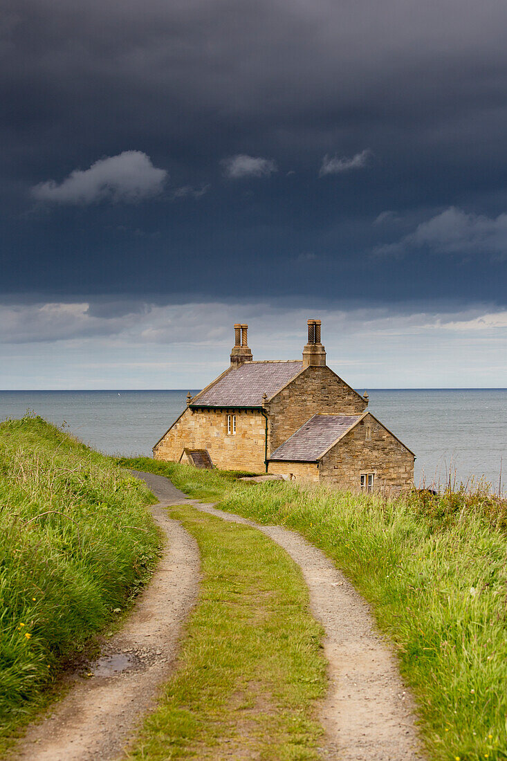 Reifenspuren im Gras, die zu einem Haus am Wasser führen; Northumberland England
