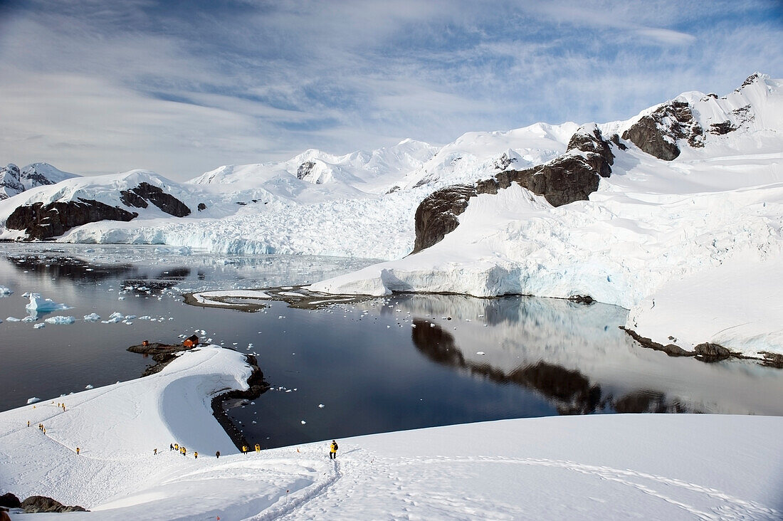 Touristen in gelben Jacken erkunden die Küstenlinie; Antarktis